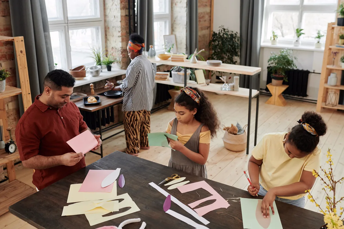 Adults and children doing a paper craft project together at home