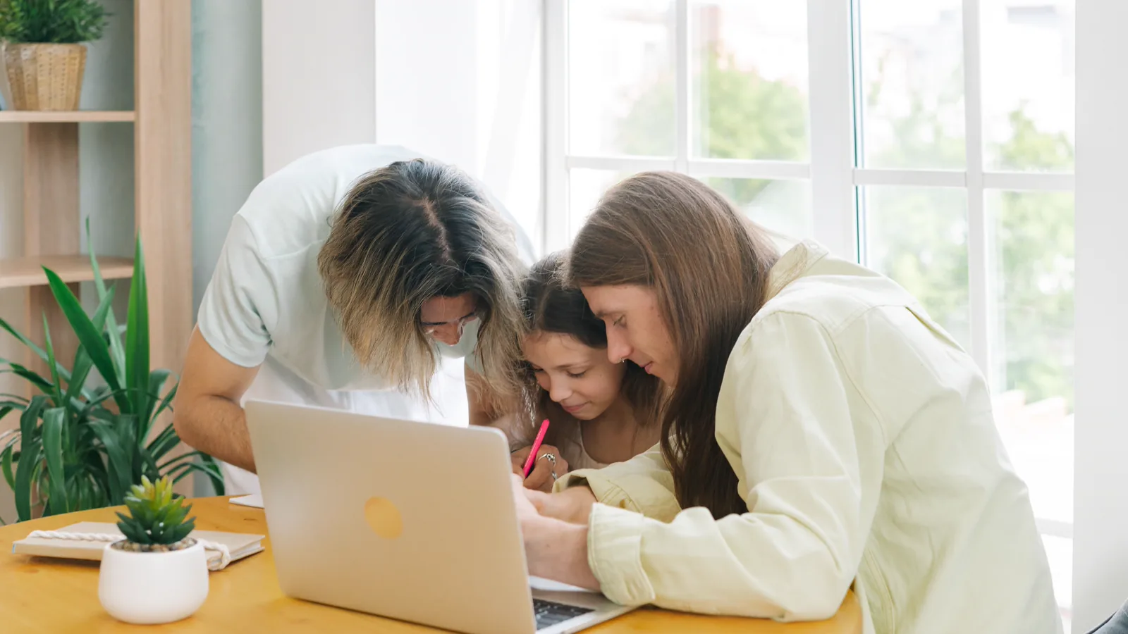 Two adults and a child working together at a table